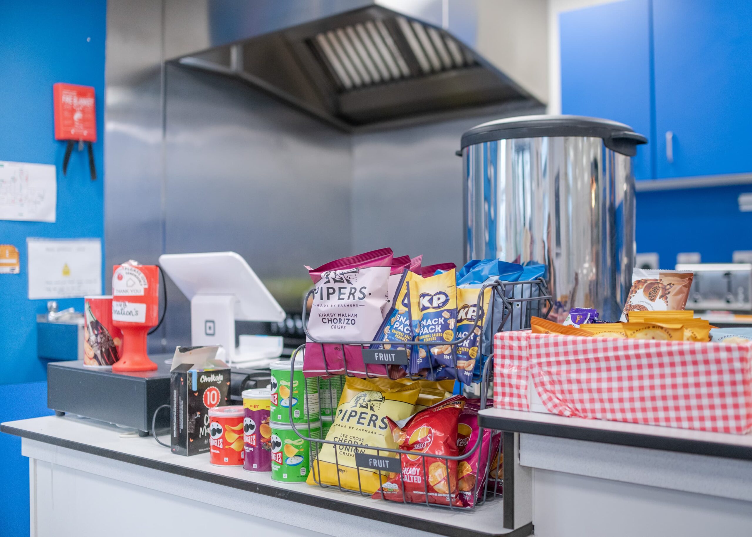 the counter at Peachey's Cafe shows a selection of biscuits, crisps, nuts and pringles available to purchase at checkout